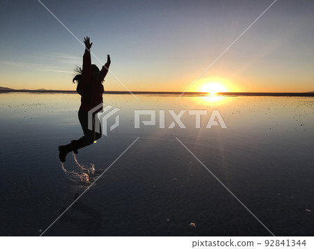 人們在黃昏時在烏尤尼鹽灘的背景下跳躍 92841344