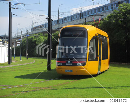 LRT tracked train (tram) running on the road surface of Songjiang district and Shanghai subway line 9 running above LRT tracked train (tram) running on the road surface of Songjiang district and Shanghai subway line 9 running above 92841372