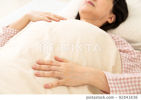 A middle-aged woman wearing pajamas and sleeping in her bedroom A middle-aged woman wearing pajamas and sleeping in her bedroom 92841636