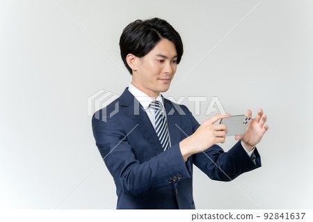 Portrait of a young businessman making a video call on a smartphone on a white background Portrait of a young businessman making a video call on a smartphone on a white background 92841637
