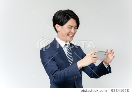 一位年輕商人在白色背景下在智能手機上進行視頻通話的肖像 一位年輕商人在白色背景下在智能手機上進行視頻通話的肖像 92841638