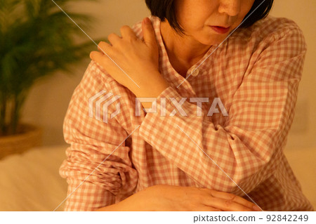 臥室裡一名穿著睡衣肩膀僵硬的中年婦女 92842249