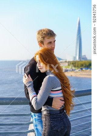 A guy and a girl are standing on the river bridge 92843756