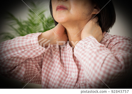 A middle-aged woman wearing pajamas and suffering from stiff shoulders in the bedroom 92843757