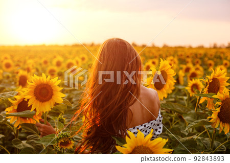 Girl with long hair stands with her back in field Girl with long hair stands with her back in field 92843893