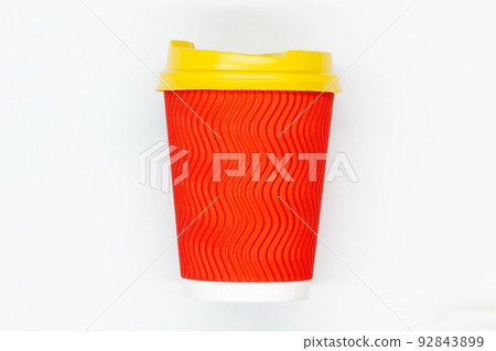 Paper coffee cup. Red craft paper coffee cup with yellow plastic lid. Disposable cup for safe drinking of hot and cold drinks. Safe ribbed capacity. Container for healthy beverage. Isolated. Close-up 92843899