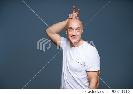 Funny bald male posing on a blue background with emotional 92843910