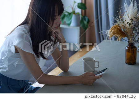 A woman staring at a smartphone with a dark expression A woman staring at a smartphone with a dark expression 92844120