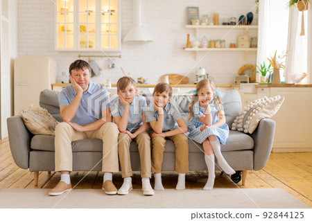 Smiling father with three small children are sitting at home on the sofa Smiling father with three small children are sitting at home on the sofa 92844125
