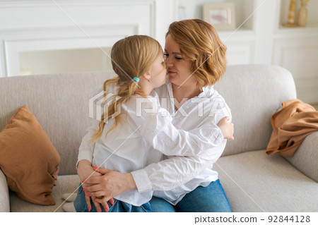 Portrait happy family, single mother and baby daughter hugging on sofa at home Portrait happy family, single mother and baby daughter hugging on sofa at home 92844128