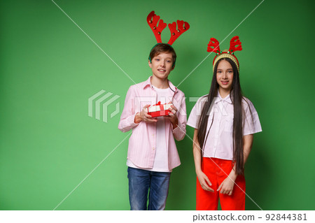 Smiling caucasian teenage couple in christmas outfit with reindeer Smiling caucasian teenage couple in christmas outfit with reindeer 92844381