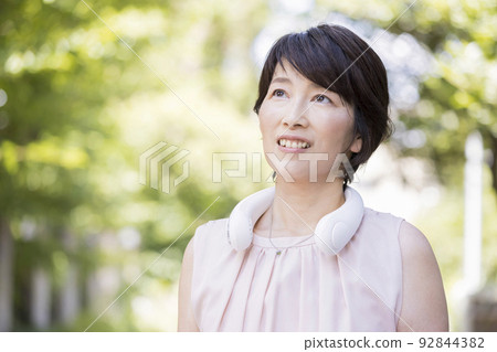 在戶外使用頸部冷卻器的中間女性頸部風扇 在戶外使用頸部冷卻器的中間女性頸部風扇 92844382