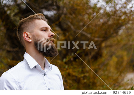 Young bearded man in white shirt walks on yellow autumn day in park. Spending Young bearded man in white shirt walks on yellow autumn day in park. Spending 92844659