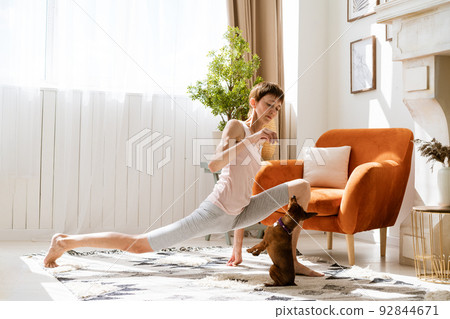 Woman doing yoga with her dog, enjoy and relax with yoga at home, relax 92844671