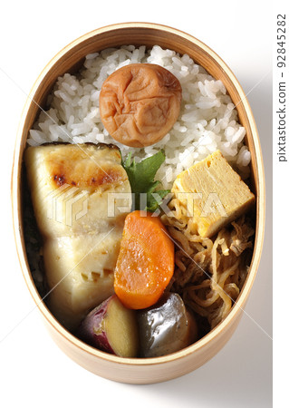 A bird's-eye view of a silver cod saikyo-yaki bento box with a large umeboshi on top of rice and tamagoyaki and simmered dishes on a white background A bird's-eye view of a silver cod saikyo-yaki bento box with a large umeboshi on top of rice and tamagoyaki and simmered dishes on a white background 92845282
