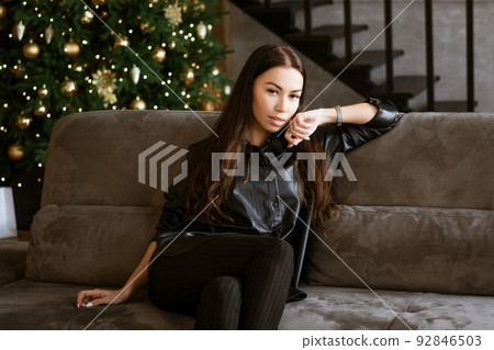 portrait of a beautiful young woman sitting on a sofa 92846503