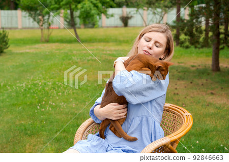 Happy woman in blue dress holding ginger imitation cat outside, outdoors Happy woman in blue dress holding ginger imitation cat outside, outdoors 92846663