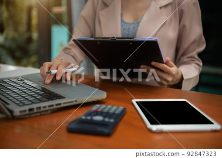 Business women calculate and analyzing graph document financial with laptop at desk. 92847323