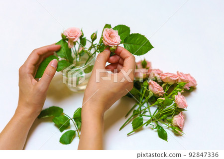 Close up of young woman florist hand creating bouquet of pink roses on a light Close up of young woman florist hand creating bouquet of pink roses on a light 92847336