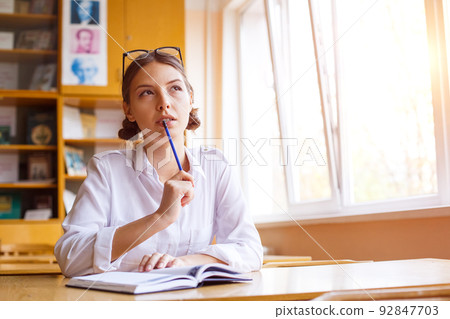 Young woman studying for test exam. Tutor writes books in notebook. Caucasian Young woman studying for test exam. Tutor writes books in notebook. Caucasian 92847703