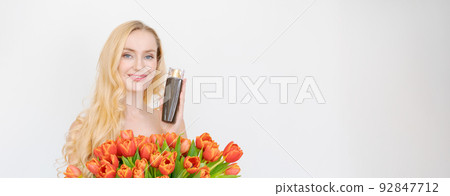 Studio portrait gorgeous blonde woman with long wavy hair holding bouquet red Studio portrait gorgeous blonde woman with long wavy hair holding bouquet red 92847712