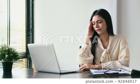 Exhausted business woman working with laptop in the office. Emotional pressure, stress at work concept Exhausted business woman working with laptop in the office. Emotional pressure, stress at work concept 92848017