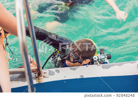 Happy diver returns to the ship after diving 92848248