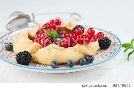 Fruit tart with red currants sprinkled with powdered sugar on a white table 92848661