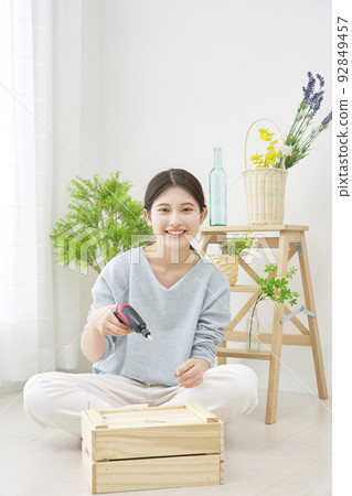 Portrait of a woman doing DIY indoors with an electric screwdriver Portrait of a woman doing DIY indoors with an electric screwdriver 92849457