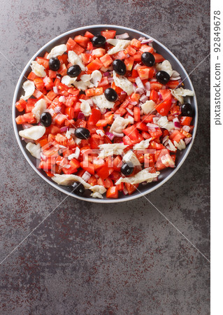 Catalan codfish salad as known as esqueixada, with cod, tomato onion and olive close-up in a plate. Vertical top view Catalan codfish salad as known as esqueixada, with cod, tomato onion and olive close-up in a plate. Vertical top view 92849678
