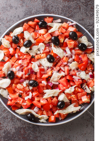 Cod esqueixada salad with tomatoes, onion and olive close-up in a plate. Vertical top view Cod esqueixada salad with tomatoes, onion and olive close-up in a plate. Vertical top view 92849679