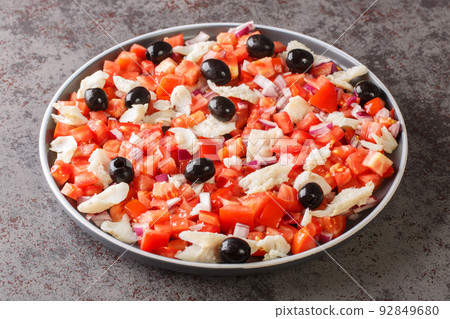 Spanish appetizer salad of salted cod, fresh tomatoes, onions and black olives close-up in a plate. horizontal Spanish appetizer salad of salted cod, fresh tomatoes, onions and black olives close-up in a plate. horizontal 92849680