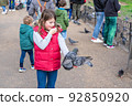 Feeding pigeons in the park. Girl feeds pigeons in London park 92850920