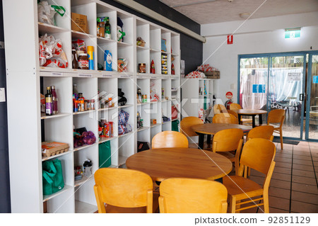 Hostel kitchen, lots of groceries and empty tables 92851129