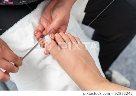 Close up photo of toenail filing. Woman get professional pedicure treatment in beauty salon. Beauty and cosmetic concept. 92852242