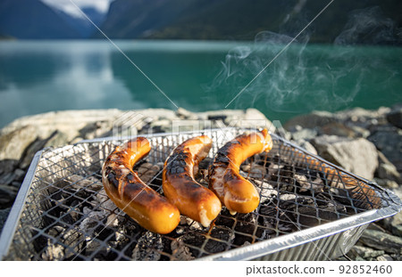 Grilling sausages on disposable barbecue grid. Grilling sausages on disposable barbecue grid. 92852460