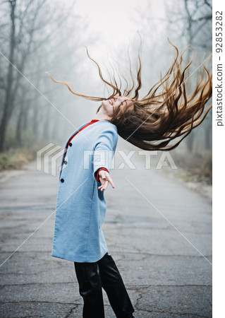 Alone Young woman with long fluttering hair express emotions in forest Alone Young woman with long fluttering hair express emotions in forest 92853282