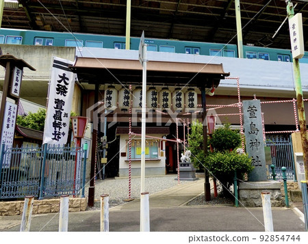 A view of the Keihan Railway beyond the Kayashima Shrine, which enshrines the sacred kaya tree that runs through the platform Neyagawa City, Osaka Prefecture 92854744