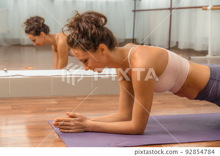 A young beautiful woman practices yoga in a yoga studio. Harmony, balance, meditation, relaxation, the concept of a healthy lifestyle A young beautiful woman practices yoga in a yoga studio. Harmony, balance, meditation, relaxation, the concept of a healthy lifestyle 92854784