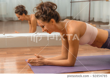 A young beautiful woman practices yoga in a yoga studio. Harmony, balance, meditation, relaxation, the concept of a healthy lifestyle A young beautiful woman practices yoga in a yoga studio. Harmony, balance, meditation, relaxation, the concept of a healthy lifestyle 92854785