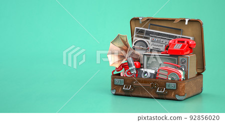 Vintage electrical and electronic appliances in an old suitcase. Nostalgic retro objects from the past 1960s - 1980s on green backgound. 92856020