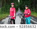Mother and daughter with bicycles in sportive suits look at camera 92856632