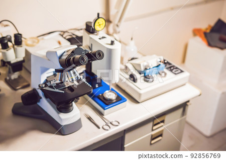 A sample preparation table in a laboratory with an optical microscope, ultrasonic cutter system and precision micrometer grinder polishing machine 92856769