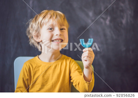 Three-year old boy shows myofunctional trainer. Helps equalize the growing teeth and correct bite, develop mouth breathing habit. Corrects the position of the tongue Three-year old boy shows myofunctional trainer. Helps equalize the growing teeth and correct bite, develop mouth breathing habit. Corrects the position of the tongue 92856826