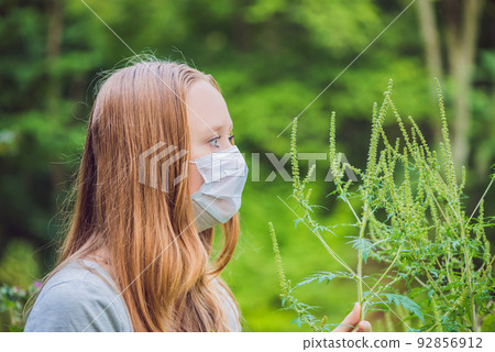 Young woman in a medical mask because of an allergy to ragweed Young woman in a medical mask because of an allergy to ragweed 92856912