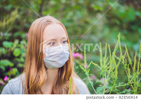Young woman in a medical mask because of an allergy to ragweed Young woman in a medical mask because of an allergy to ragweed 92856914