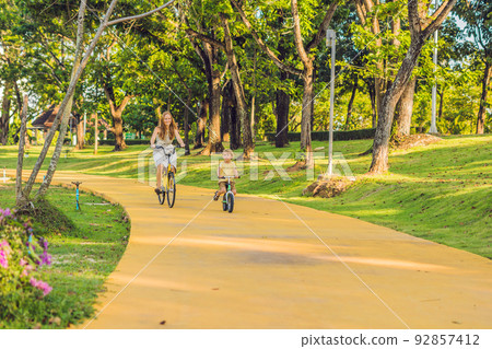 Happy family is riding bikes outdoors and smiling. Mom on a bike and son on a balancebike 92857412