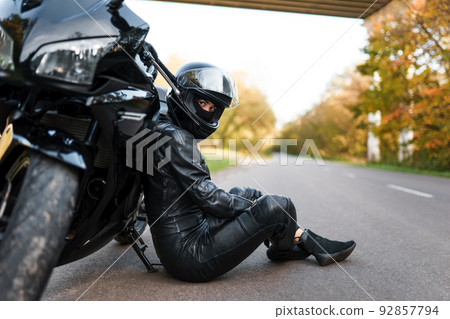 Biker girl in sits leaning on a motorcycle Biker girl in sits leaning on a motorcycle 92857794