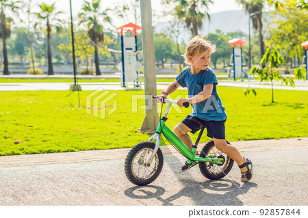 Little boy on a bicycle. Caught in motion, on a driveway. Preschool child's first day on the bike. The joy of movement. Little athlete learns to keep balance while riding a bicycle 92857844