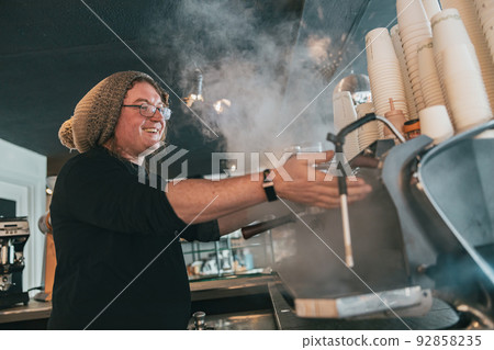 Smiling barista preparing coffee espresso in automatic coffee machine in cafe Smiling barista preparing coffee espresso in automatic coffee machine in cafe 92858235